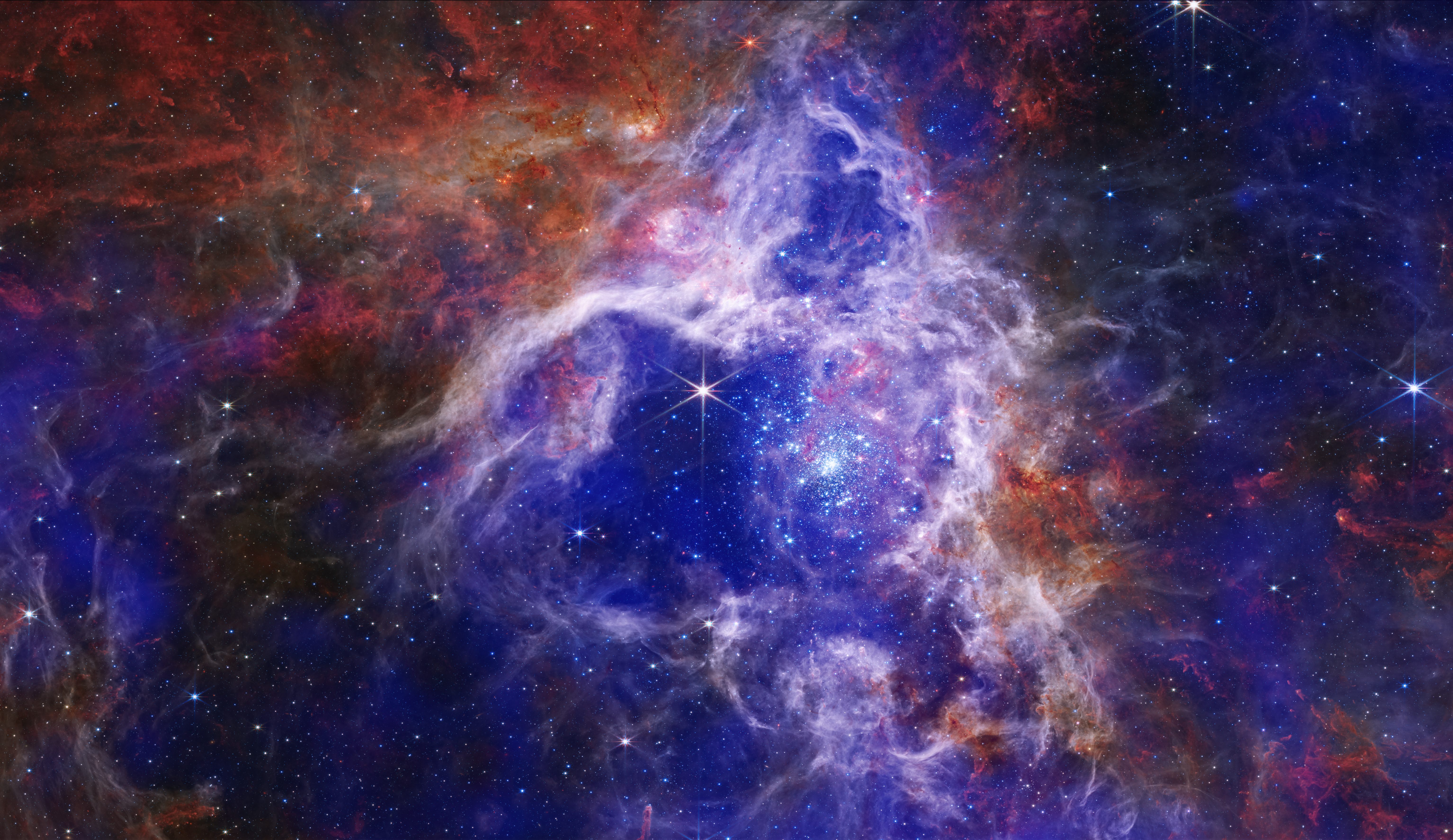 Na ilustracji (1): Połączone zdjęcia z teleskopów Chandra oraz Webba Mgławicy Tarantula w zakresie rentgenowskim (kolory: niebieski i fioletowy) i w podczerwieni (kolory: czerwony, pomarańczowy, zielony i jasnoniebieski). Widać tutaj protogwiazdy i masywne obłoki gazu i pyłu, w których powstają gwiazdy. Źródło: X-ray: NASA/CXC/Penn State Univ./L. Townsley et al.; IR: NASA/ESA/CSA/STScI/JWST ERO Production Team