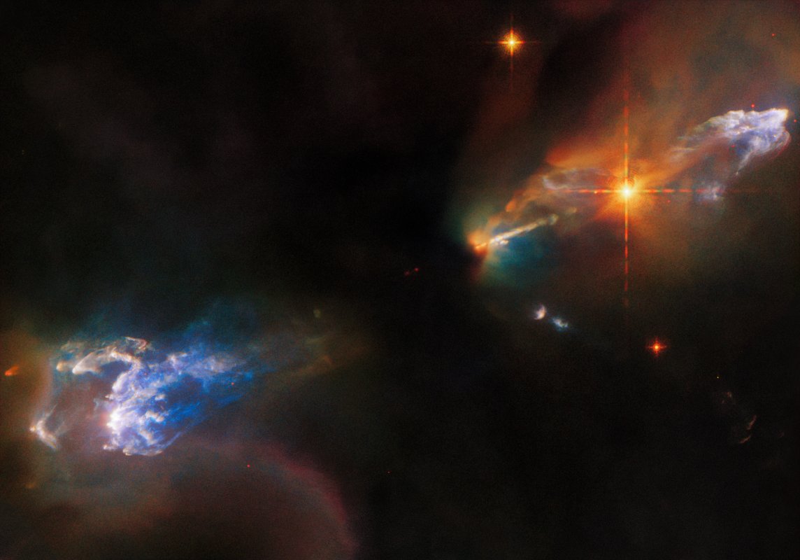 Na ilustracji:widać obiekty Herbiga-Haro (HH), czyli dwa drobne obłoki gazowe: HH 1-u góry po prawej, HH 2-na dole po lewej.Obie mgławice HH świecą na niebiesko i są otoczone przez ciemniejsze,wielobarwne obłoki. Widać również bardzo jasną, pomarańczową gwiazdę na lewo poniżej HH1. Za tą gwiazdą znajduje się wąski dżet, który wyrzuciła jedna z gwiazd schowanych za ciemnym obłokiem w centralnej części zdjęcia. Ten obraz sfotografował Kosmiczny Teleskop Hubble'a. Źródło:ESA/Hubble & NASA, B.Reipurth, B.Nisini