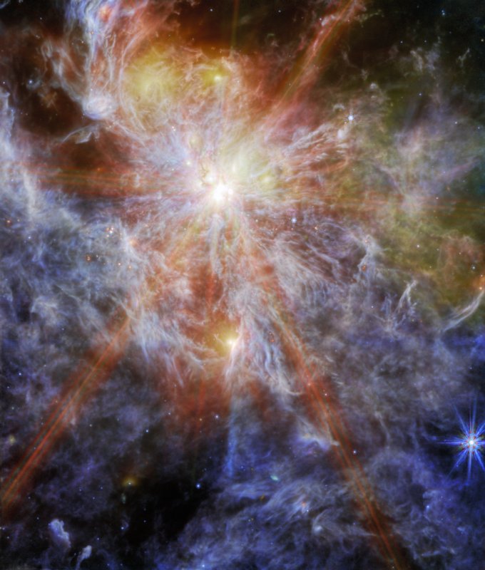 Na ilustracji: Widać obszar gwiazdotwórczy N79 (S1) w Wielkim Obłoku Magellana z obłokami zjonizowanego wodoru (H II), które sfotografowano przez instrument MIRI współpracujący z Teleskopem Webba. Głównym obiektem jest masywna i młoda gwiazda intensywnie oświetlająca otaczającą mgławicę, która mieni się feerią barw. Ta gwiazda wygląda na zdjęciu jak najjaśniejsza plamka, a od niej rozchodzi się osiem promieni świetlnych (j.t. efekt instrumentalny Teleskopu Webba). Źródło: NASA/ESA/CSA/M. Meixner