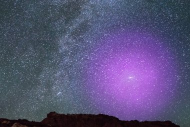 Wizualizacja przedstawia halo gazowe wokół galaktyki M31, gdyby było widoczne gołym okiem. Z odległości 2.5 mln lat świetlnych ogromna galaktyka spiralna w Andromedzie jest tak blisko, że wydaje się być smugą światła w kształcie papierosa wznoszącą się wysoko na tle jesiennego nieba. Gdyby to gazowe halo mogło być widoczne gołym okiem, to byłoby jedną z największych struktur na nocnym niebie (ok.3x większe od Wielkiego Wozu). Źródło: NASA, ESA, J. DePasquale i E. Wheatley (STScI), i Z.Levay (obraz w tle).