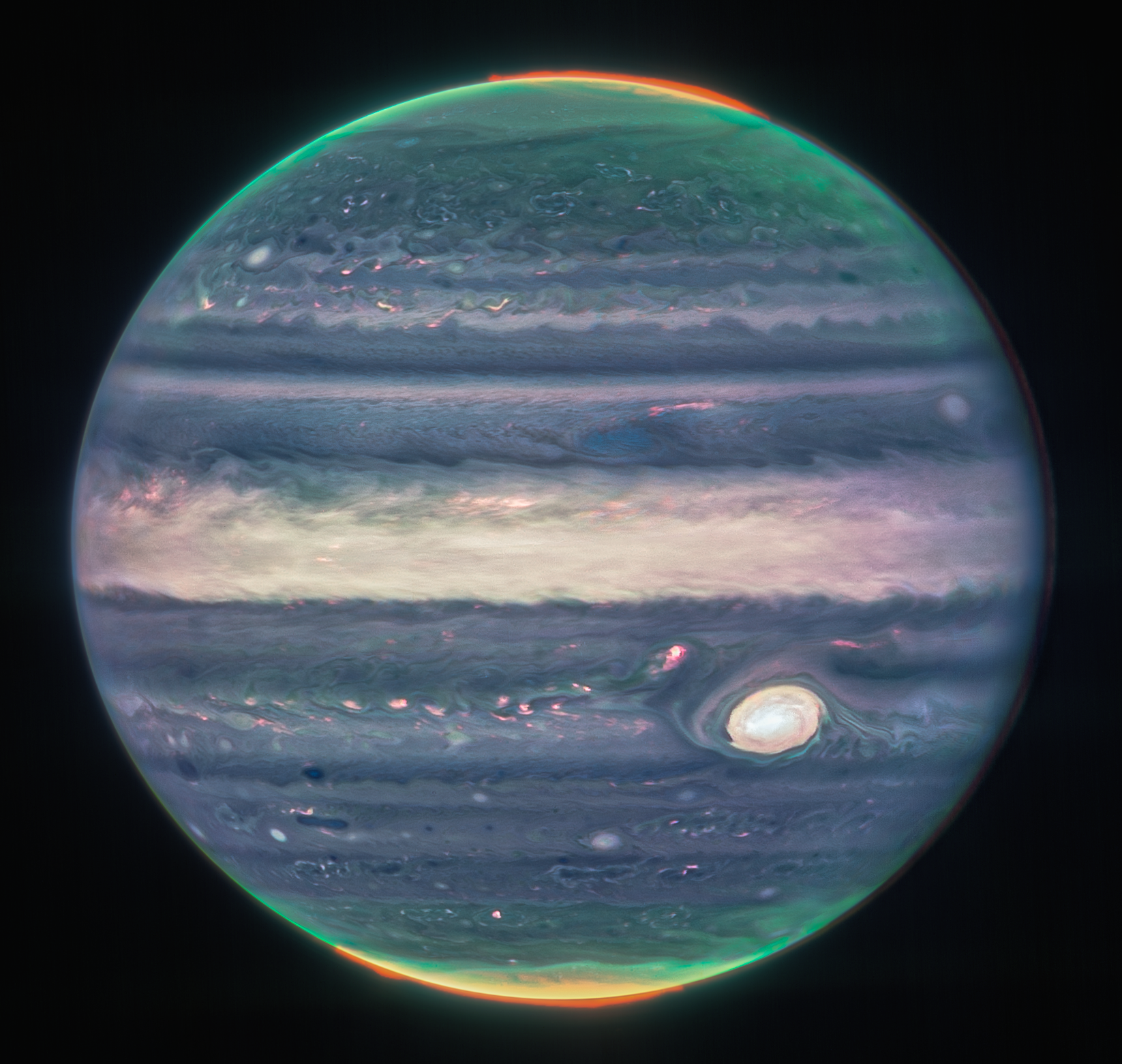 Na ilustracji: Zdjęcie Jowisza zrobione Teleskopem Webba z kamerą NIRCam w trzech barwach / filtrach – F360M (czerwony), F212N (żółto-zielony) i F150W2 (cyjan/niebieskozielony) z uwzględnieniem rotacji planety. Na zdjęciu nad północnym i południowym biegunem Jowisza widać zorze polarne mapowane odcieniami koloru czerwonego. Ten kolor posiada również światło odbite od niżej położonych chmur oraz zamgleń w górnej części atmosfery Jowisza. Odcieniami koloru żółtego i zielonego są mapowane zamglenia wirujące wokół północnego i południowego bieguna planety. Natomiast kolorem niebieskim jest mapowane światło, które odbija się od głębszej, głównej warstwy chmur atmosfery Jowisza. Źródło: NASA, ESA, CSA, Jupiter ERS Team; opracowanie zdjęcia Judy Schmidt (projekt nauki obywatelskiej)