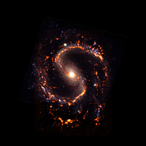 NGC 4535, wspaniała galaktyka spiralna z poprzeczką. Na tym złożonym zdjęciu obłoki molekularne sfotografowane przez radioteleskopy ALMA są przedstawione w kolorze pomarańczowym i czerwonym i nałożone na obraz optyczny z Kosmicznego Teleskopu Hubble'a.