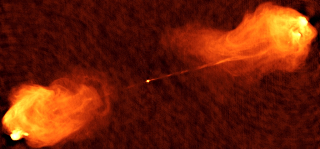 Cygnus A – obraz typowej radiogalaktyki. Jądro radiowe znajdujące się w centrum niezbyt odległej galaktyki (przesunięcie ku czerwieni z ~ 0,06) jest stowarzyszone z supermasywną (ok. 2,5 miliardów mas Słońca) czarną dziurą. 