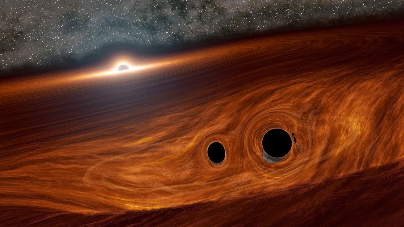 Wizja artystyczna supermasywnej czarnej dziury J1249+3449 (... w oddali) o masie rzędu 100 mln Mʘ otoczonej przez dysk akrecyjny. Na skraju tego dysku w odległości ~ 700 j.a. widzimy dwie znacznie mniejsze czarne dziury o sumarycznej masie ~100 Mʘ, orbitujące wokół wspólnego środka masy na chwilę przed ich koalescencją (połączeniem się), które zostało oznaczone w literaturze naukowej symbolem S190521g. Źródło: R Hurt (IPAC)/Caltech.