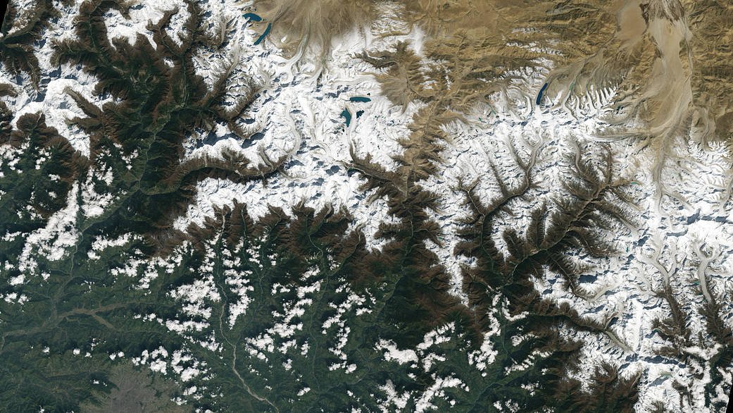 Miasto Katmandu, stolica Nepalu, widoczne jest w lewym dolnym rogu zdjęcia z satelity Landsat 9. Katmandu leży w dolinie na południe od Himalajów. Lodowce i jeziora utworzone przez wody polodowcowe są widoczne w górnej części ujęcia. Źródło: NASA/Landsat 9.