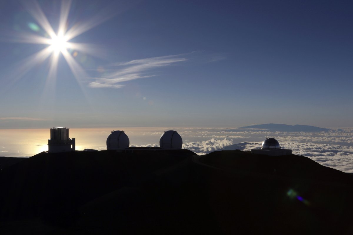 Słońce zachodzące za teleskopami na szczycie Mauna Kea na Hawajach, 14 lipca 2019 r. Na ponad 50 lat teleskopy zdominowały górę świętą dla Hawajczyków i zarazem jedno z najlepszych miejsc na świecie do badania nieba. Źródło: AP Photo/Caleb Jones