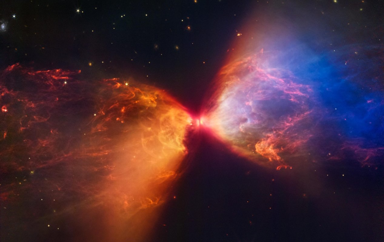 Na ilustracji widać obraz protogwiazdy w ciemnej mgławicy L1527, który uzyskał Kosmiczny Teleskop Jamesa Webba (kamera NIRCam → ~0,3 l.św. po przekątnej). Protogwiazda jest zanurzona w chmurze materii, którą akreuje i przez to staje się coraz cięższa. Wyrzuty materii z protogwiazdy wyczyściły przestrzeń po obu stronach tego ciemnego obłoku, którego granice mają barwę pomarańczową i niebieską na tym zdjęciu w bliskiej podczerwieni. Źródło: NASA, ESA, CSA,  STScI. J. DePasquale, A. Pagan, A. Koekemoer (STScI)