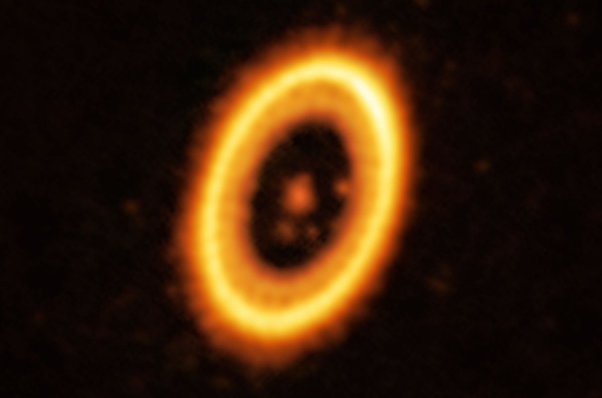 Na tym obrazie radiowym PDS 70 plama znajdująca się poniżej gwiazdy centralnej jest olbrzymią protoplanetą. Tuż po jej prawej stronie znajduje się obłok pyłu, który może być formującą się planetą. Kolejną protoplanetę można dostrzec na prawo od gwiazdy, tuż wewnątrz jasnego pierścienia pyłu. Źródło: ALMA; ESO/NAOJ/NRAO; Balsalobre-Ruza et al.