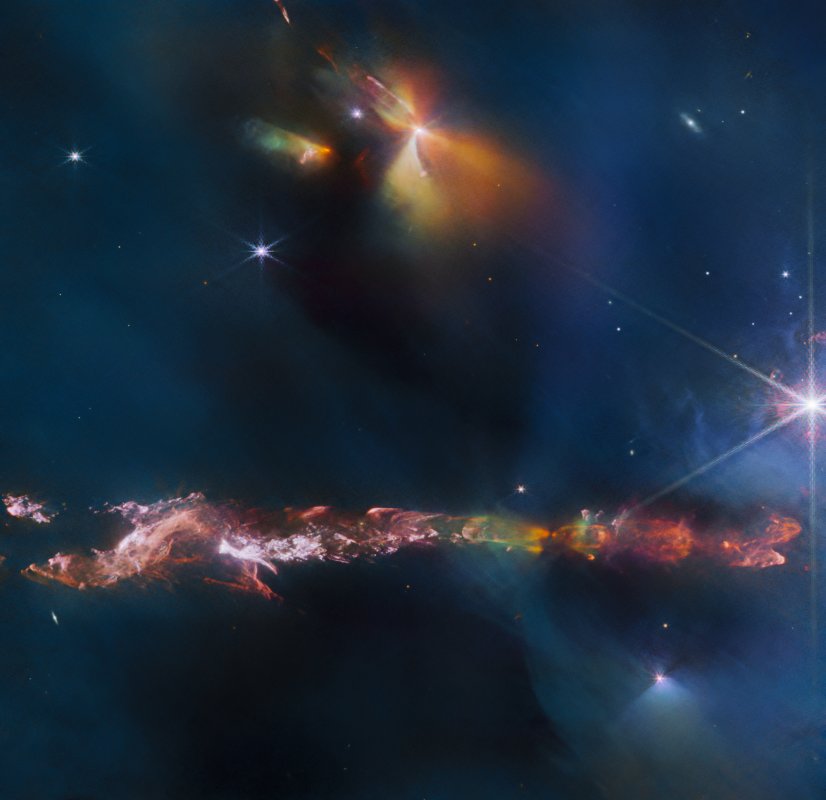 Na ilustracji: Obraz okolic obiektu Herbig-Haro 797 (HH 797) sfotografowany w bliskiej podczerwieni (8 barw o długościach fali od 1,64 μm do 4,7 μm) przez kamerę NIRCam znajdującą się na pokładzie Kosmicznego Teleskopu Jamesa Webba. W dolnej części jego części widać wąską mgławicę o jaskrawych barwach rozciągającą się poziomo przez cały kadr – z większą różnorodnością po jej prawej stronie.  Źródło: ESA/Webb, NASA & CSA, T. Ray (Dublin Institute for Advanced Studies)