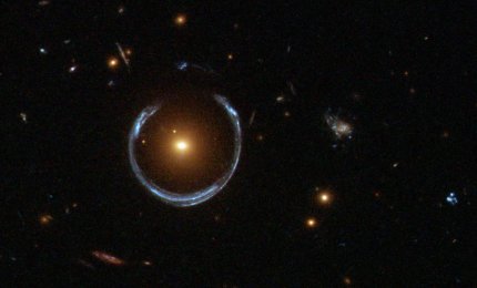 Obraz odległej, niebieskiej galaktyki zniekształcony przez efekt soczewkowania grawitacyjnego przez czerwoną galaktykę znajdującą się na pierwszym planie