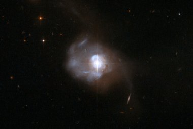 Optyczny obraz jasnej galaktyki Markarian 231 wykonany przez Kosmiczny Teleskop Hubble'a. Obserwacje w podczerwieni na linii OH pokazały obecność silnego wiatru wiejącego z centralnych obszarów. Najnowsze badania przedstawiają analizę takich wiatrów dla łącznie 24 galaktyk. Źródło: NASA/Hubble