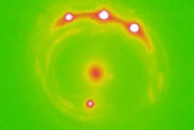 Zniekształcony obraz optyczny jednego z obserwowanych kwazarów. Plama w centrum to soczewkująca galaktyka, cztery jasne plamy to obrazy tego samego obiektu. 
