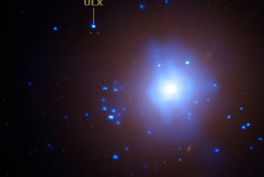 Galaktyka eliptyczna NGC 1399: kolorem niebieskim przedstawiono emisję promieniowania X nałożoną na zdjęcie optyczne. Na zdjęciu zaznaczono położenie źródła ULX. Źródło: X-ray: NASA/CXC/UA/J. Irwin; Optical: NASA/STScI