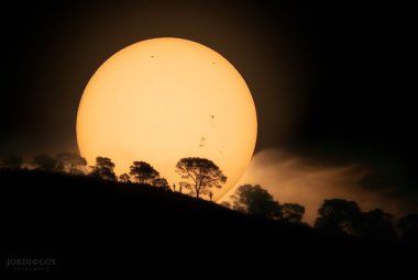 Czy ta olbrzymia pomarańczowa kula zaraz stoczy się po porośniętym drzewami wzgórzu? Nie, ponieważ ta kula to tak naprawdę nasze Słońce. Centralna gwiazda Układu Słonecznego została uchwycona o wschodzie, ponad wzgórzem na Ziemi, dwanaście dni temu – wraz z uroczo szczegółowym pierwszym planem. Na tarczy Słońca widać pięć plam słonecznych. To całkiem sporo, biorąc pod uwagę fakt, że w okresie minimum cyklu aktywności słonecznej w ciągu ostatnich kilku lat przez większość dni w ogóle nie było plam. Źródło: A