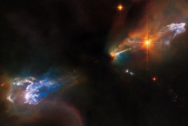 Na ilustracji:widać obiekty Herbiga-Haro (HH), czyli dwa drobne obłoki gazowe: HH 1-u góry po prawej, HH 2-na dole po lewej.Obie mgławice HH świecą na niebiesko i są otoczone przez ciemniejsze,wielobarwne obłoki. Widać również bardzo jasną, pomarańczową gwiazdę na lewo poniżej HH1. Za tą gwiazdą znajduje się wąski dżet, który wyrzuciła jedna z gwiazd schowanych za ciemnym obłokiem w centralnej części zdjęcia. Ten obraz sfotografował Kosmiczny Teleskop Hubble'a. Źródło:ESA/Hubble & NASA, B.Reipurth, B.Nisini