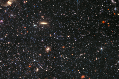 Zdjęcie wykonane przez kamerę NIRCam Kosmicznego Teleskopu Jamesa Webba, na którym widać fragment karłowatej galaktyki nieregularnej Wolf-Lundmark-Melotte, jak również w tle wiele galaktyk. To zdjęcie pokazuje niezwykłą zdolność teleskopu Webba do detekcji słabych gwiazd poza Drogą Mleczną. Pole widzenia obejmuje około 2’ (~1700 l.św. przy odległości do galaktyki WLM). Źródło: NASA / ESA / CSA / STScI / K. McQuinn, Rutgers University / A. Pagan, STScI.