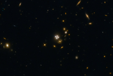 w samym centrum zdjęcia widzimy kwazar soczewkowany grawitacyjnie przez galaktykę znajdującą się przed nim, dużo bliżej ziemskiego teleskopu, który je sfotografował. Cztery równo ułożone punkty wokół niego to obrazy tego samego kwazara, powstałe właśnie poprzez grawitacyjne zakrzywianie promieni światła przez soczewkującą galaktykę na pierwszym planie. Źródło: ESA/Hubble, NASA, Suyu et al. (Lensed quasar and its surroundings, ESA/Hubble (esahubble.org)) 