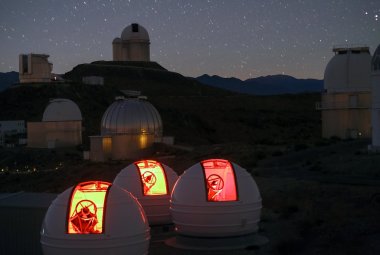 Nocny widok pokazuje na pierwszym planie trzy kopuły ExTra oraz w tle wiele innych teleskopów w Obserwatorium La Silla. Źródło: ESO/Emmanuela Rimbaud