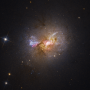 Zdjęcie robione przez Kosmiczny Teleskop Hubble’a w zakresie optycznym galaktyki karłowatej Henize 2-10 mieniącej się młodymi gwiazdami. Jasny obszar w centrum otoczony przez różowe obłoki i pasy ciemnego pyłu wskazują na położenie masywnej czarnej dziury i aktywnych obszarów tworzenia się gwiazd. Źródło: NASA, ESA, Zachary Schutte (XGI), Amy Reines (XGI), Alyssa Pagan (STScI)